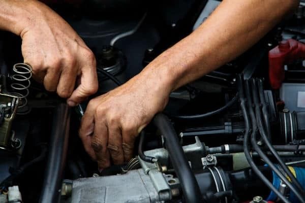A man is working on the engine of a car.