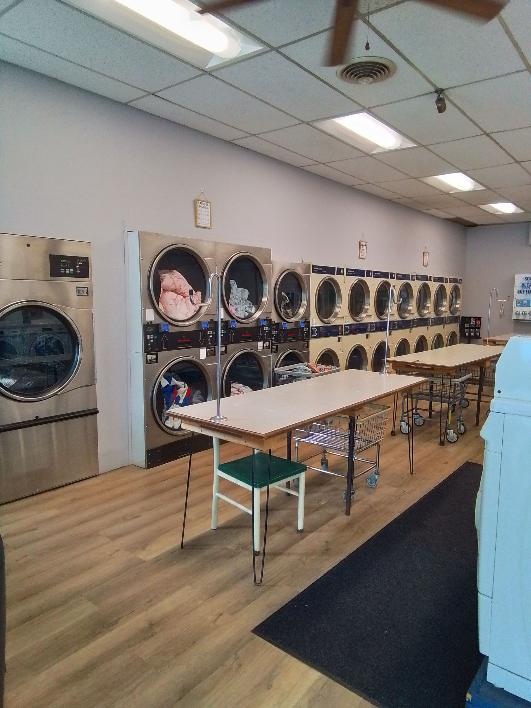 A laundry room with a washing machine , drying rack , and baskets.