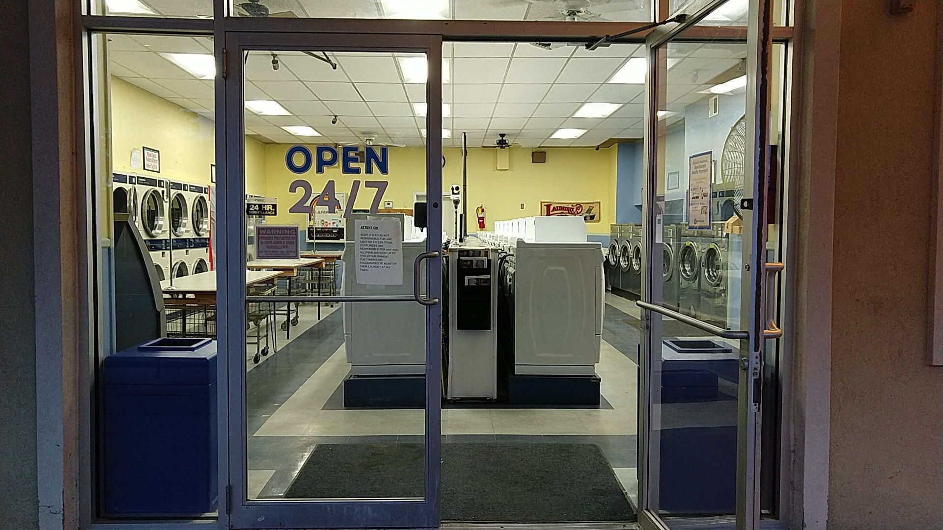 A person is putting a blue towel into a washing machine.