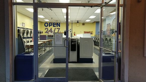 A person is putting a blue towel into a washing machine.