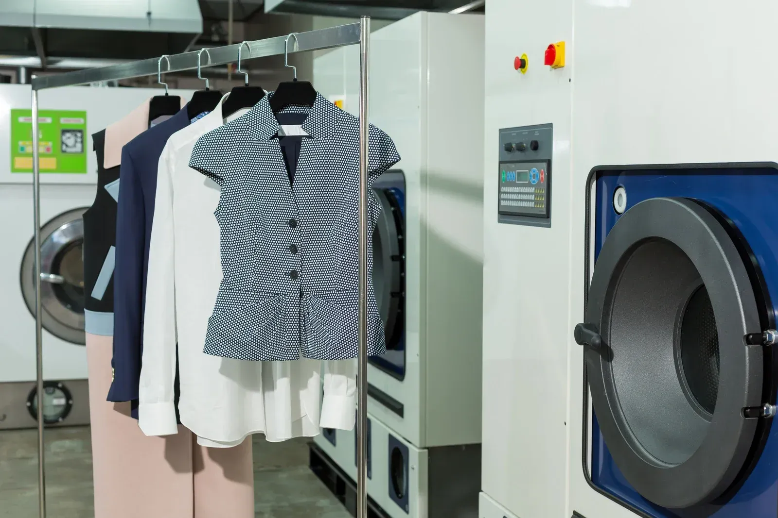 A row of blue and white shirts hanging on a rack in front of a window.