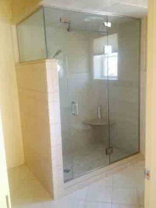 Glass shower enclosure with beige tile walls, a built-in seat, and chrome hardware.