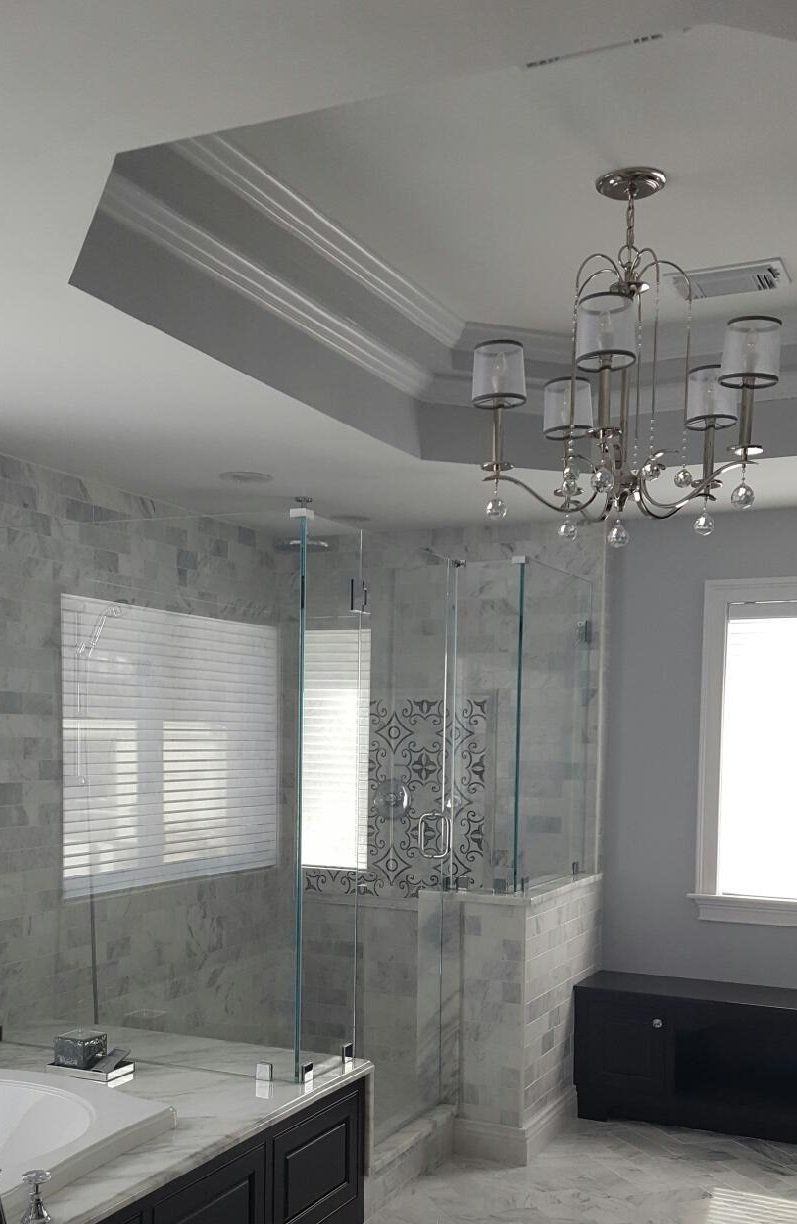 Bathroom with a glass shower, chandelier, and marble tiling.