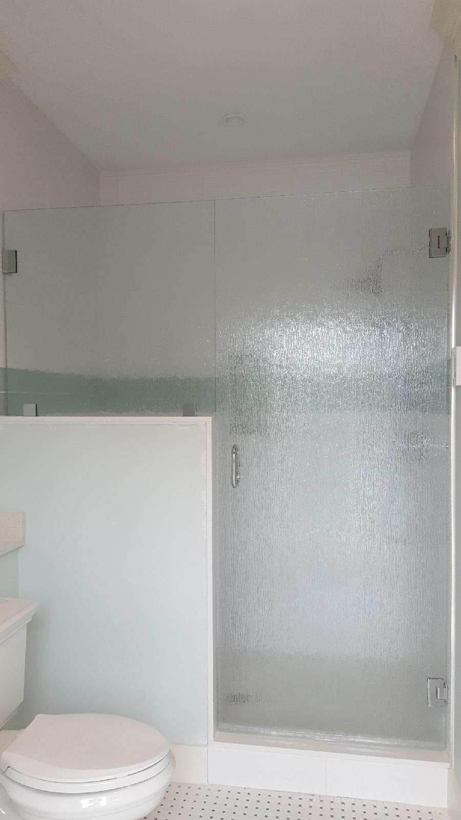 Frosted glass shower door and wall next to a white toilet, in a bathroom.