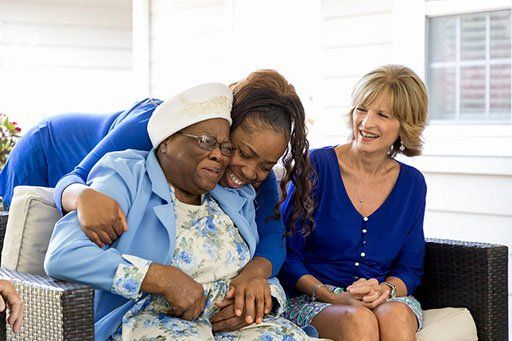 A group of women are sitting on a couch hugging each other.
