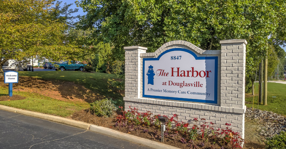 A sign for the harbor is sitting on the side of a road.