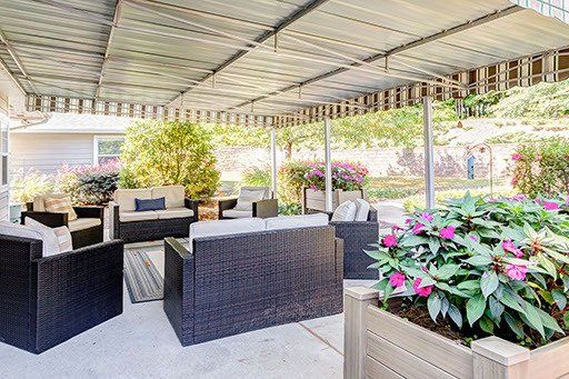 A patio with furniture and flowers under a canopy.