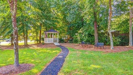 A path leading to a gazebo in a park surrounded by trees.