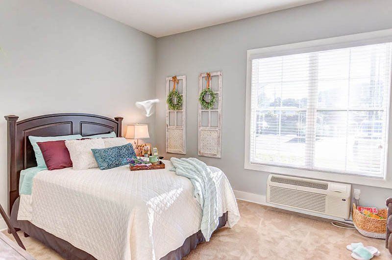 A bedroom with a bed , window and air conditioner.
