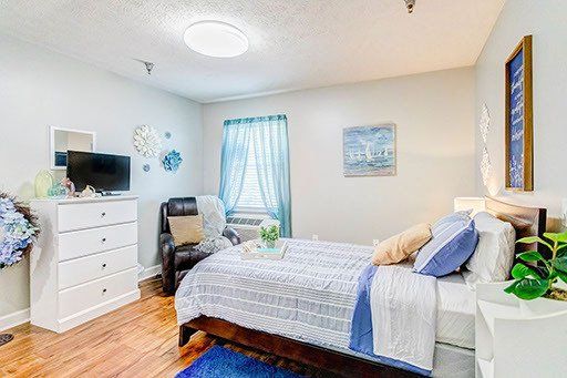 A bedroom with a bed , dresser , chair and television.