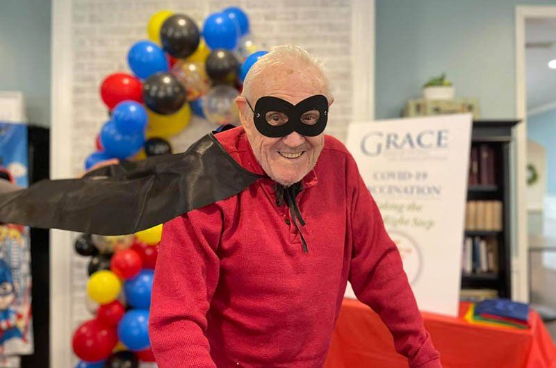 An elderly man is wearing a mask and a bat costume.