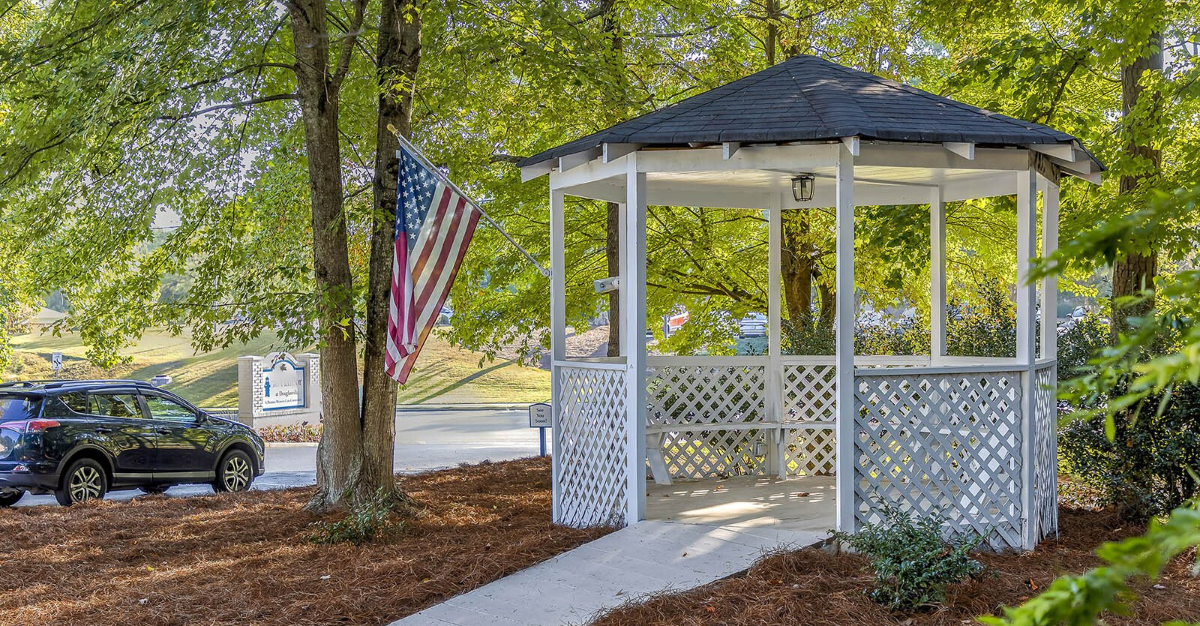 A gazebo with an american flag on top of it in a park.