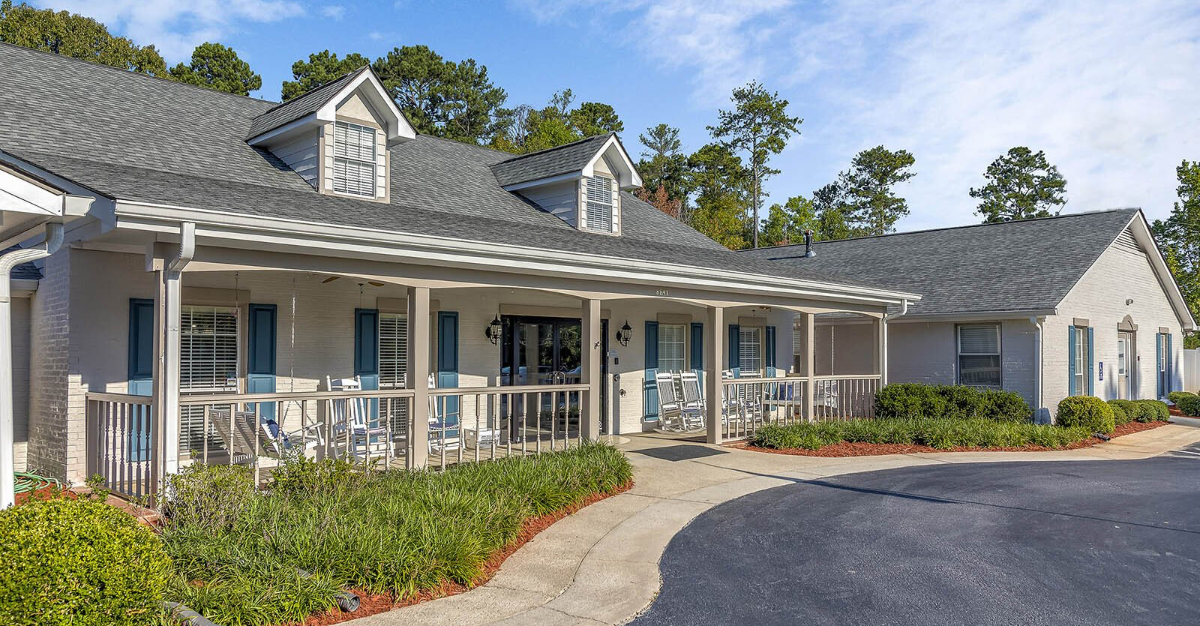 A large white house with a large porch and a gray roof.