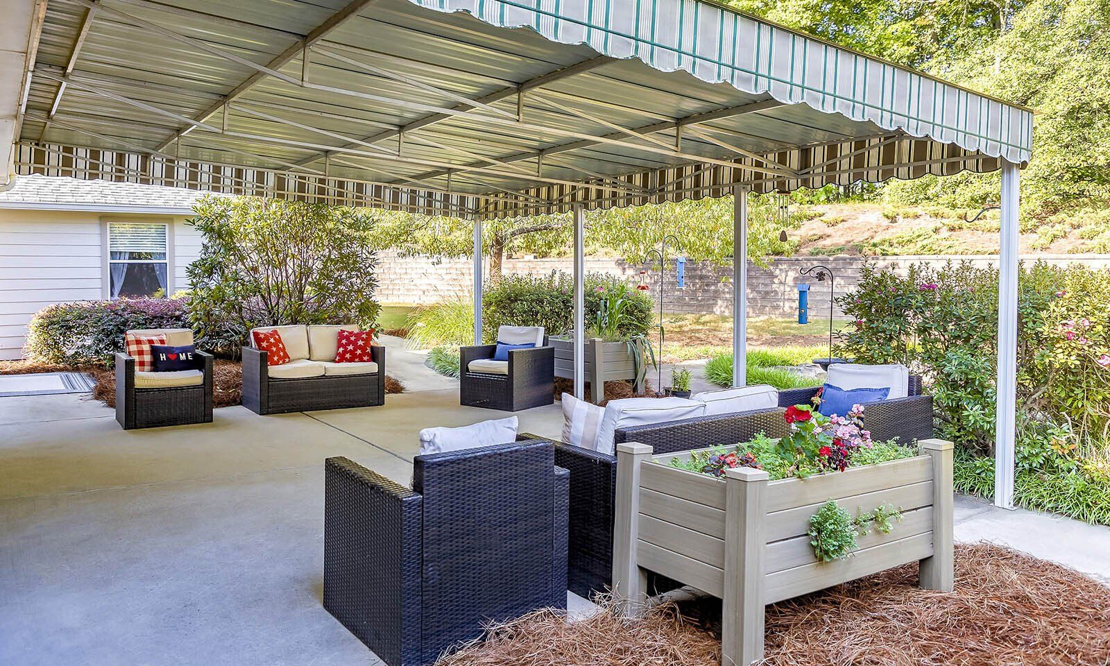 A patio with furniture and a planter under a canopy.