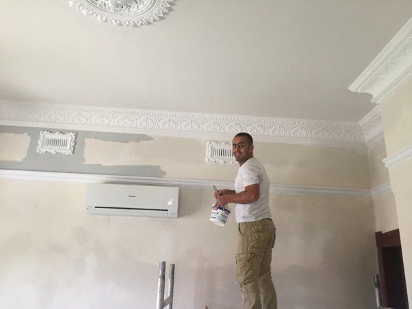 man smiling while working on ceiling