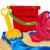 A red bucket with a green handle and a yellow shovel in the sandbox