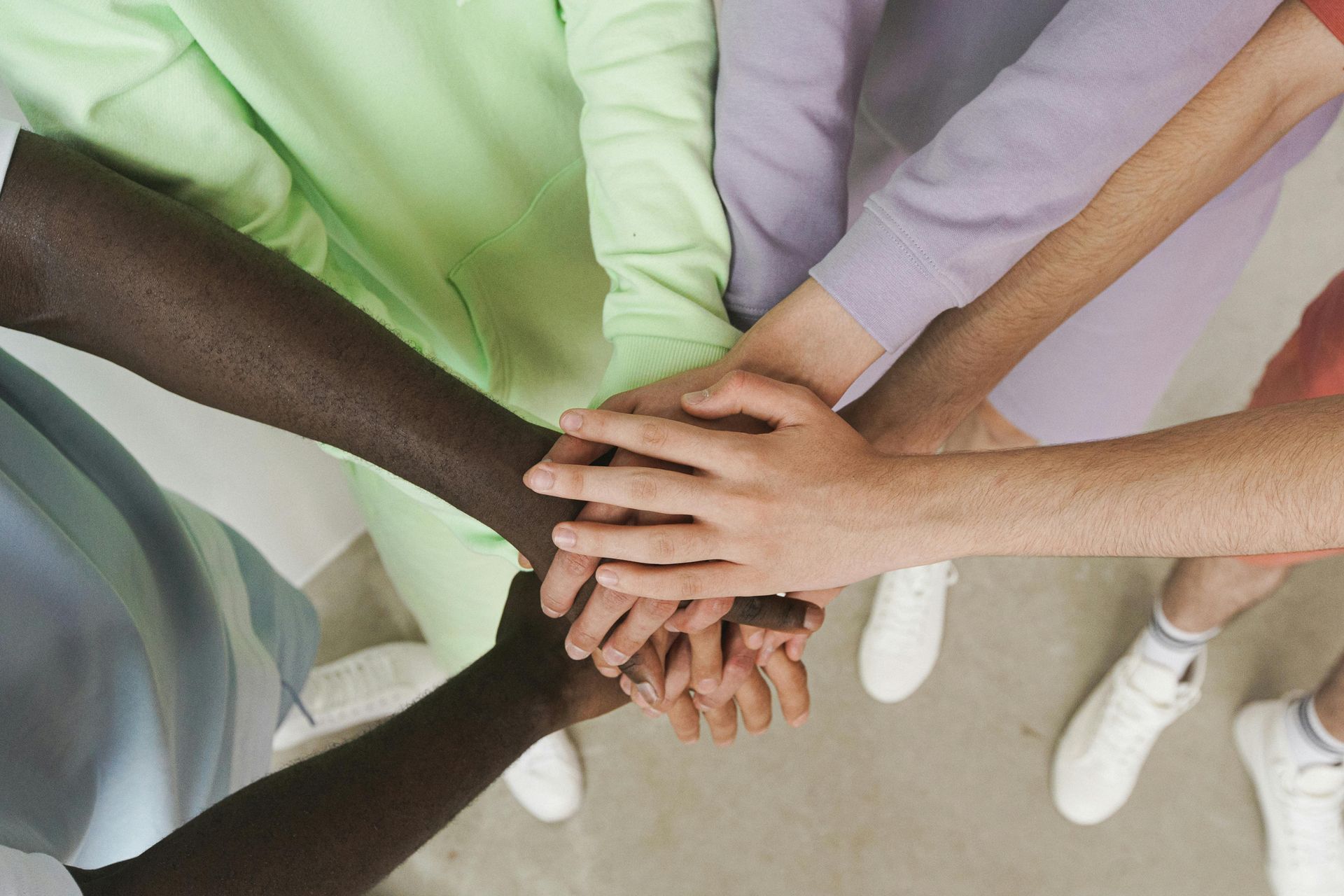 Hands stacked together in a group, diverse skin tones, collaborative gesture.