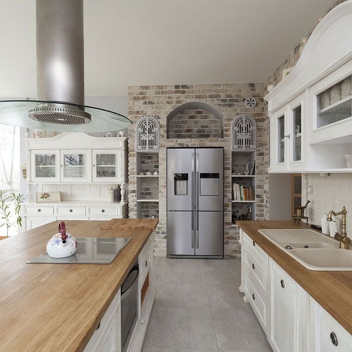 A kitchen with white cabinets and a stainless steel refrigerator