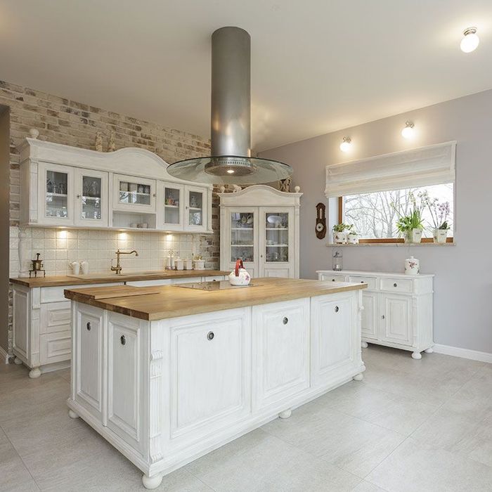 A kitchen with white cabinets and a large island in the middle