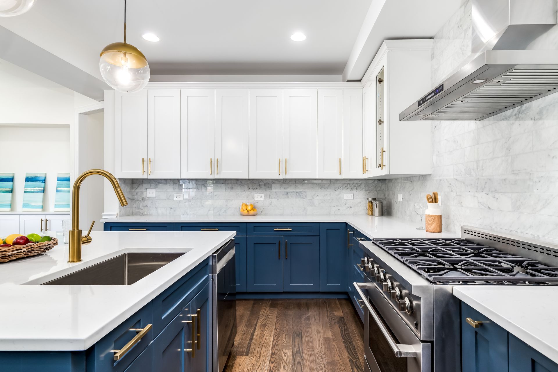 A kitchen with blue cabinets , white cabinets , stainless steel appliances , a sink and a stove.