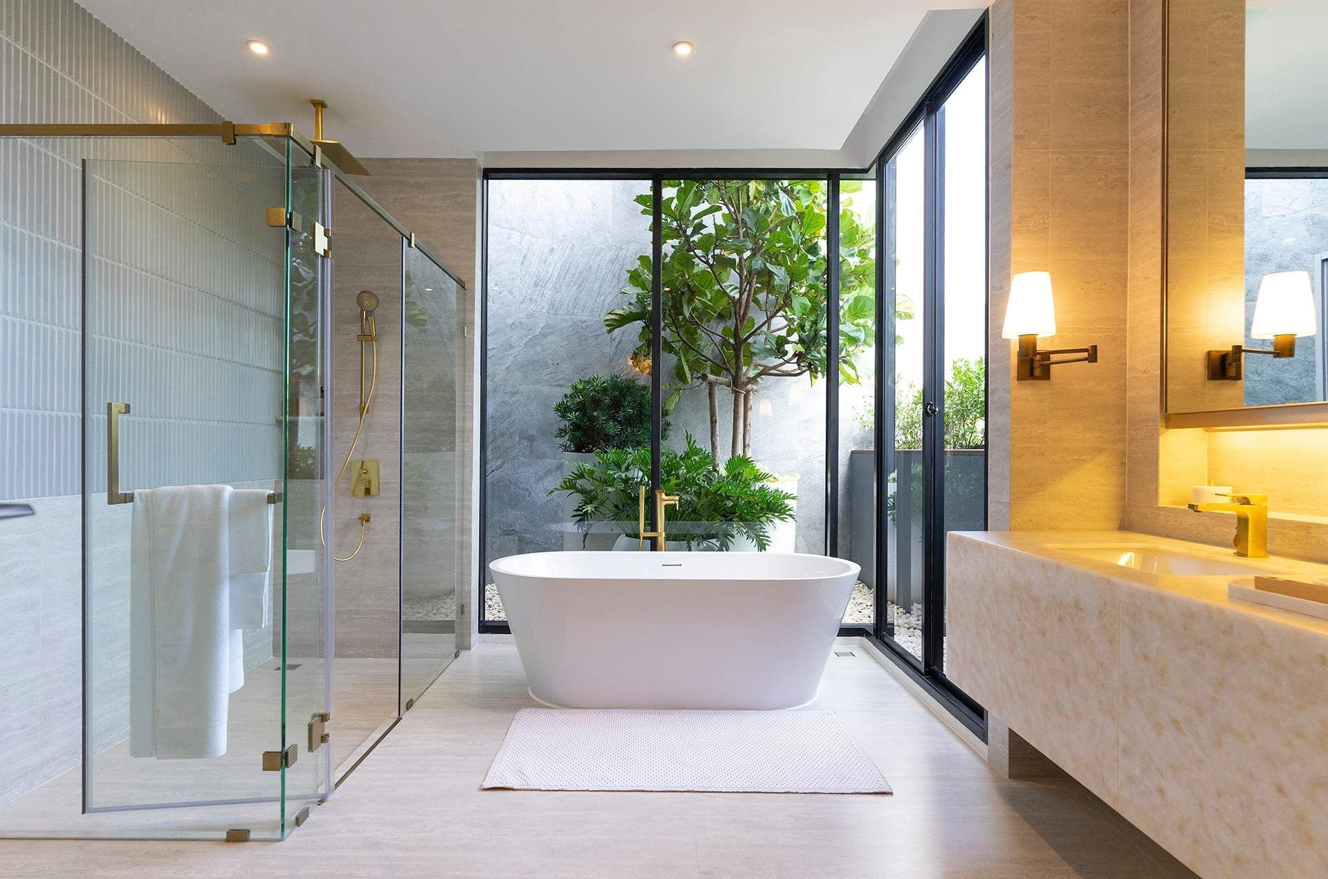 A bathroom with a bathtub , sink , shower and large windows.