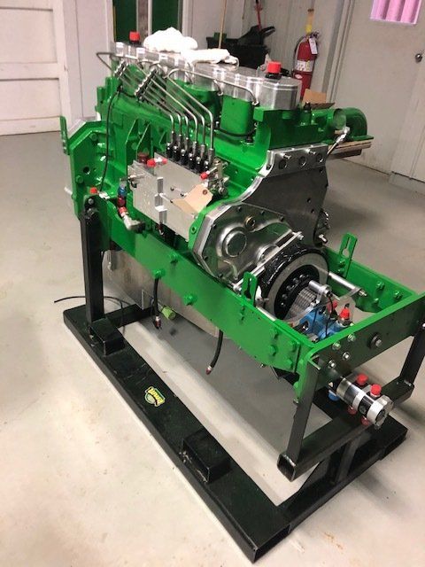 Green engine assembly mounted on a black stand in a workshop.