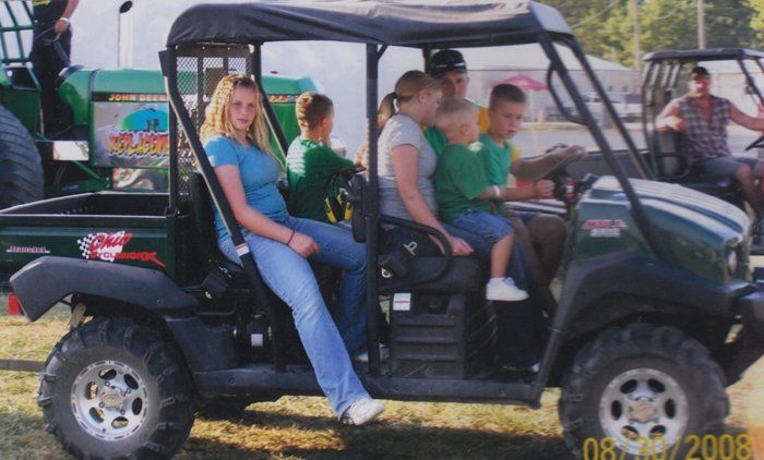 People riding in a utility vehicle at an outdoor event.