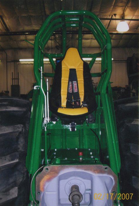 Green tractor with yellow racing seat and roll cage.