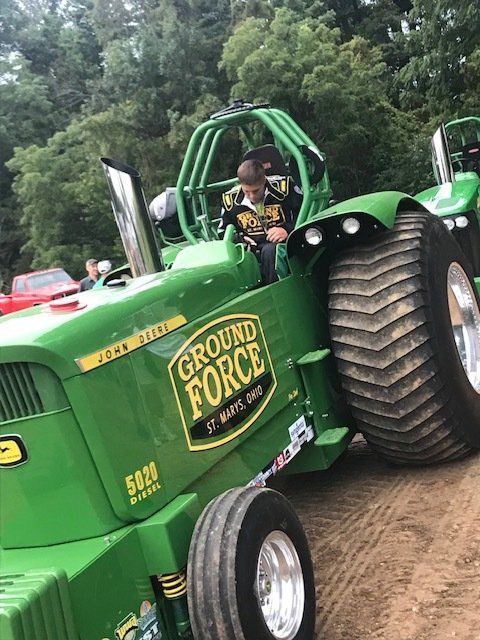 A young person in a green tractor labeled 