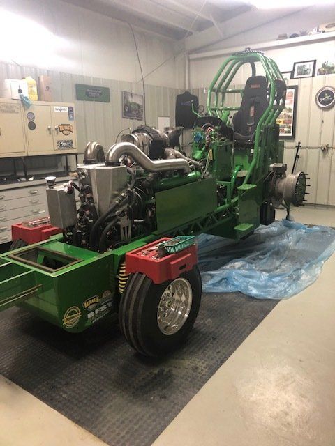 Green modified tractor in a shop.