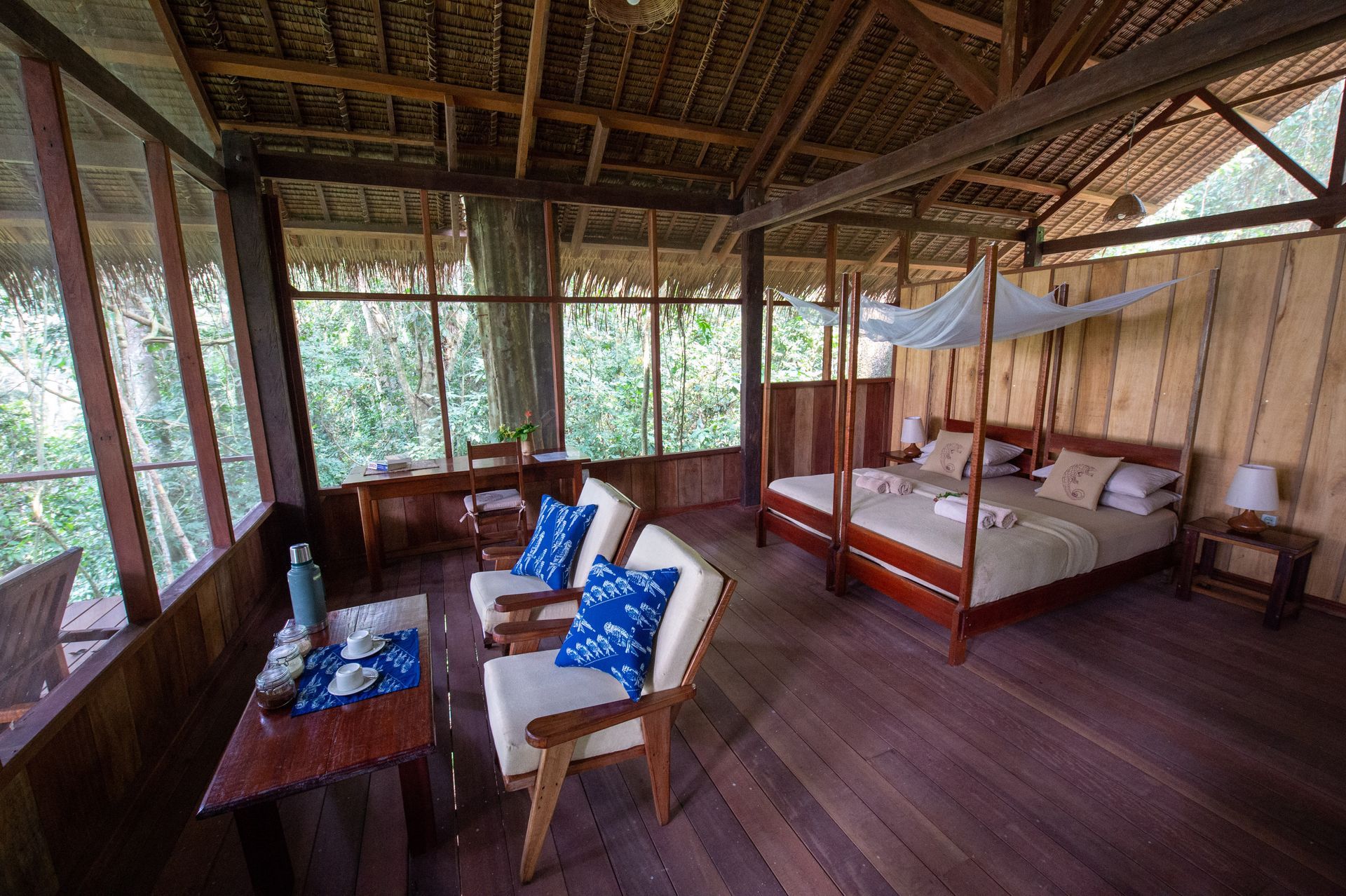 A room with a canopy bed , chairs , and a table.