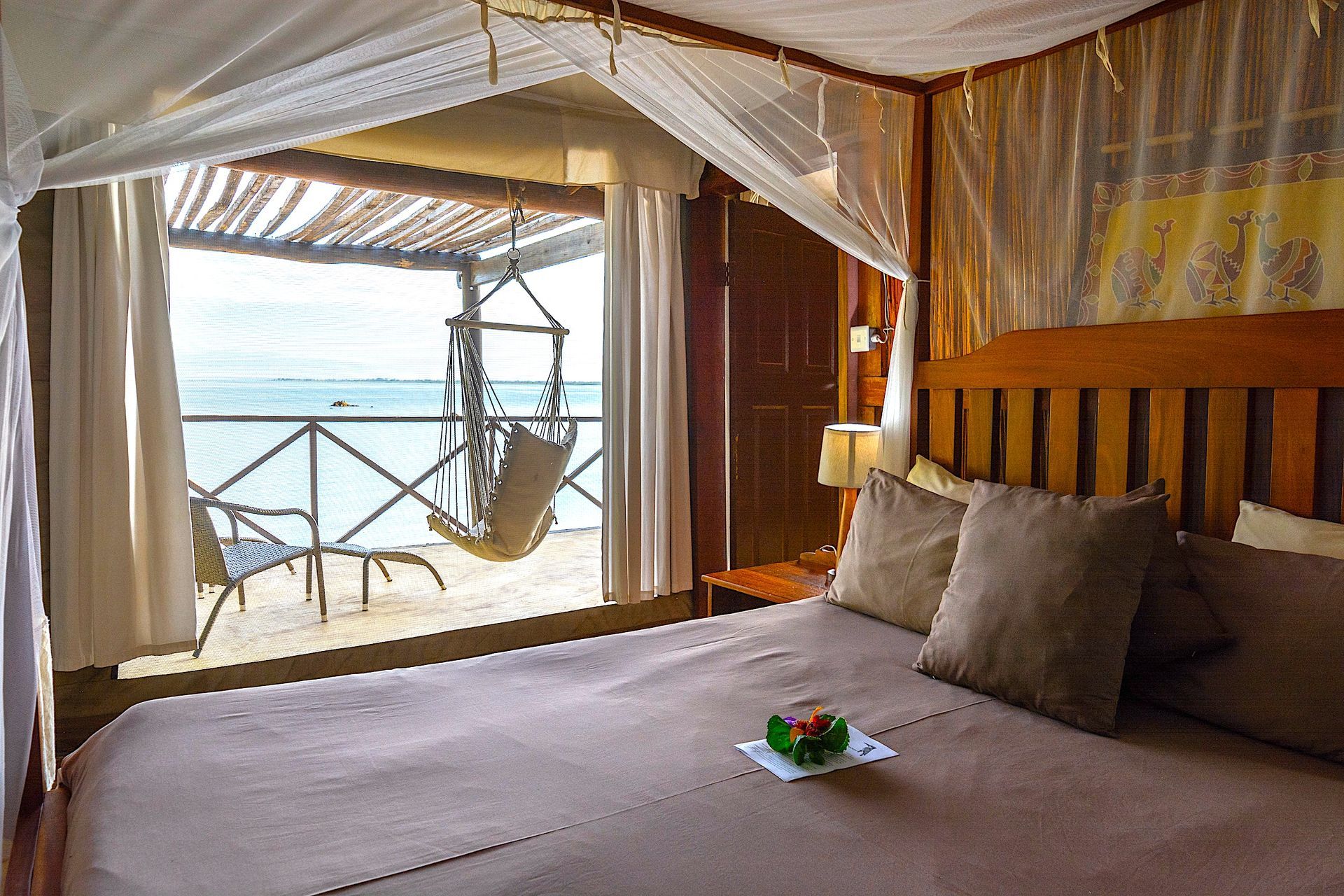 A bedroom with a canopy bed and a balcony overlooking the ocean.