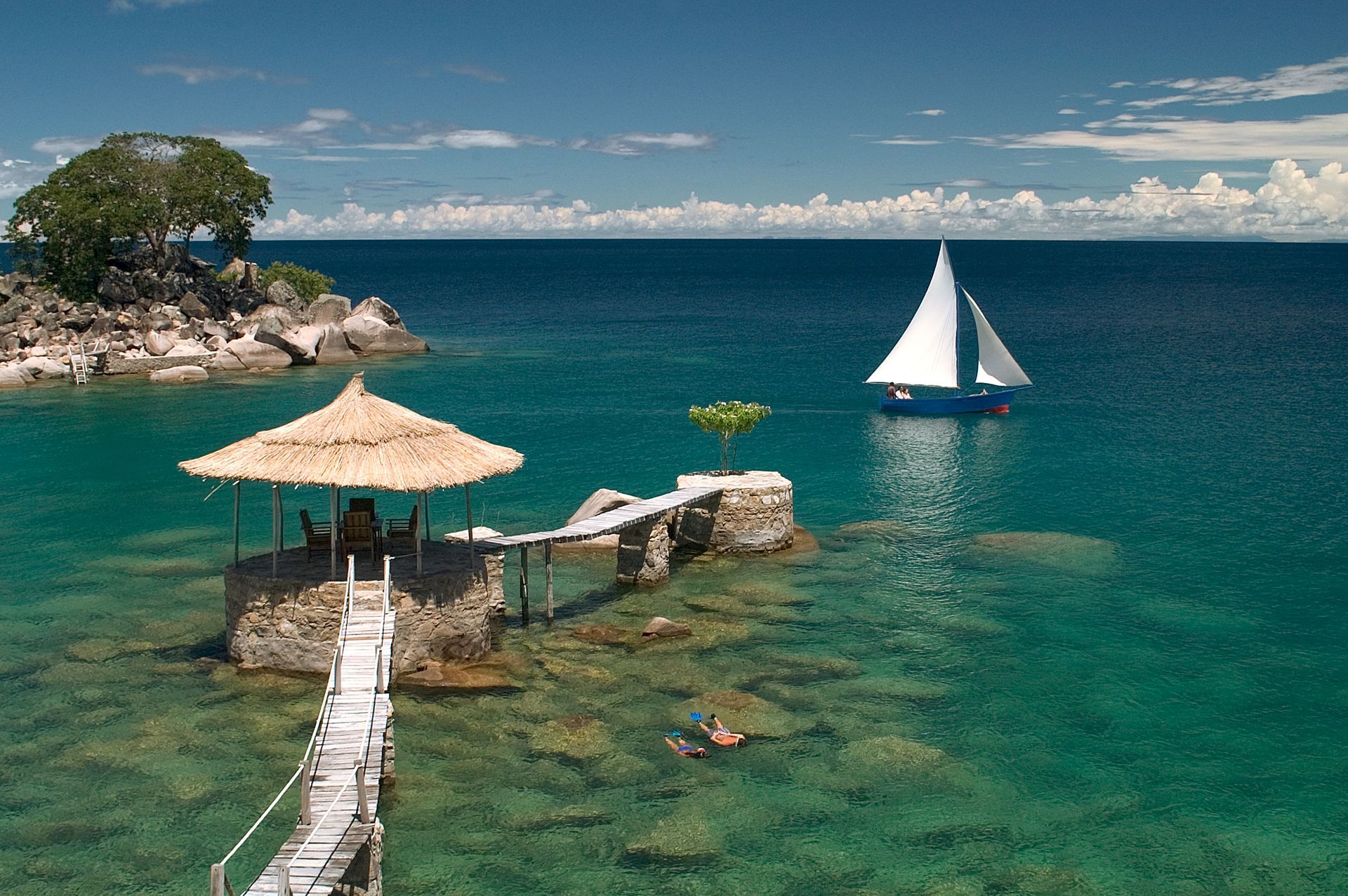 A sailboat is floating in the ocean near a dock