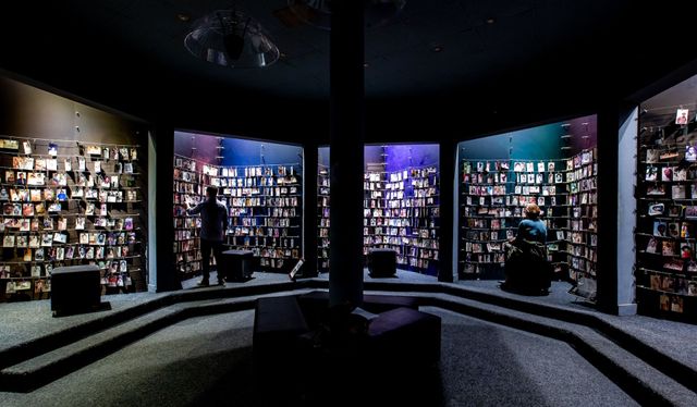 A man is standing in a room with a lot of bookshelves.