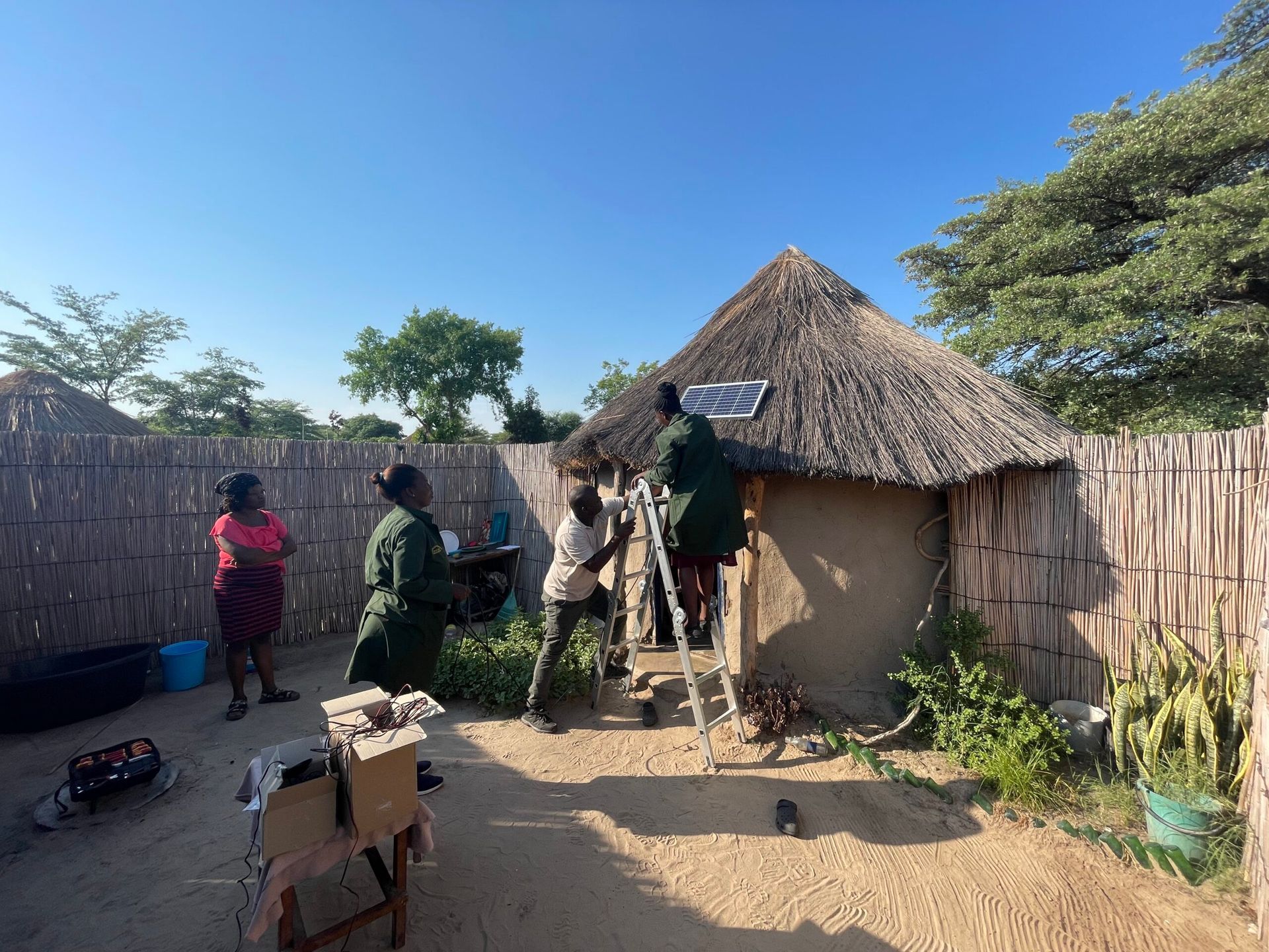 A group of people are working on a thatched hut.