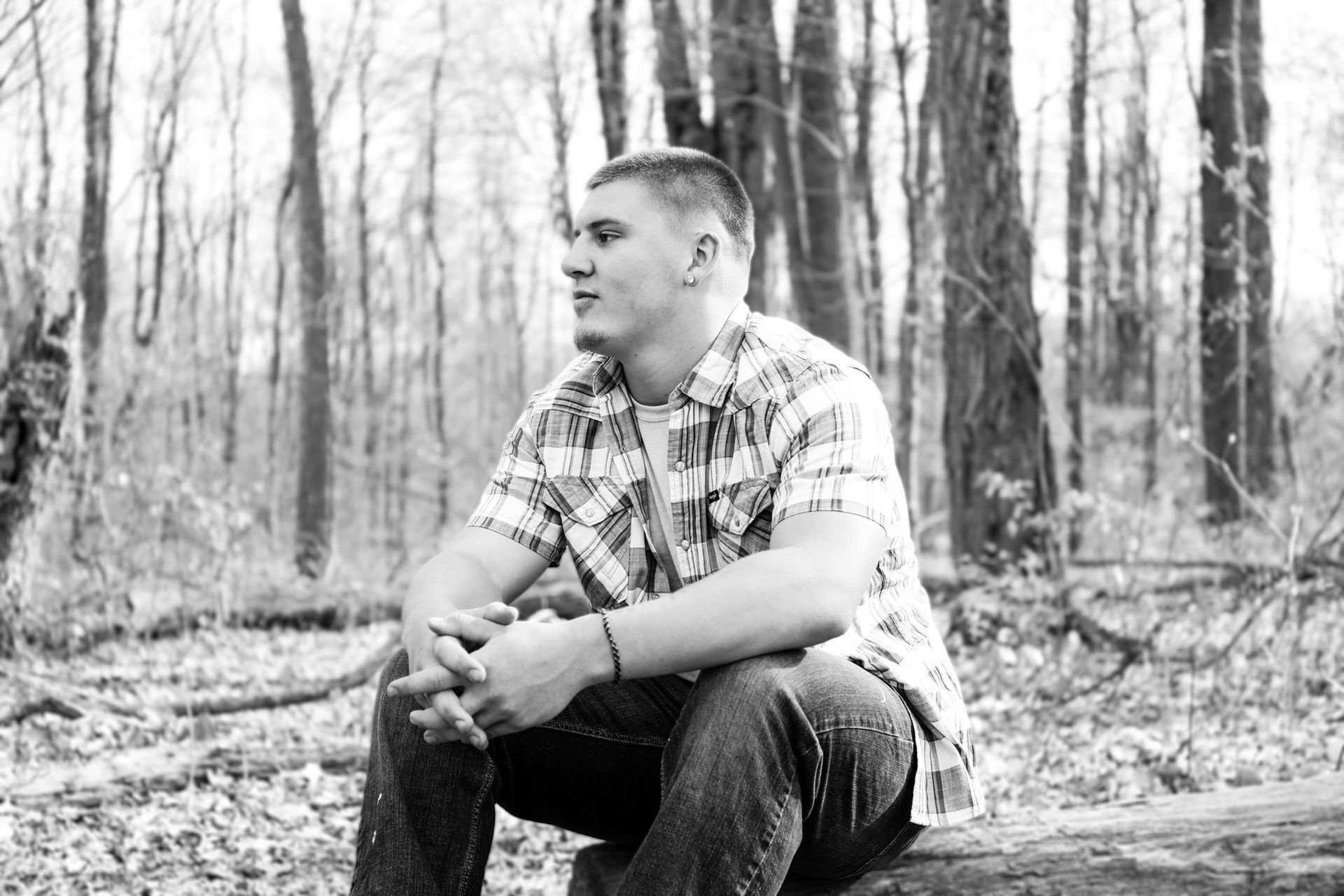 A man is sitting on a log in the woods.