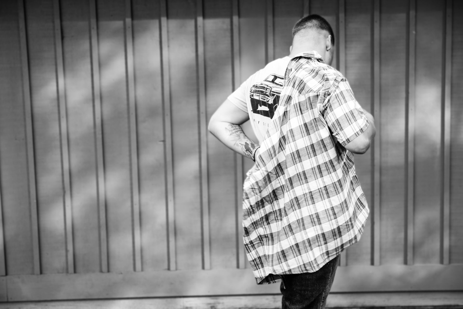 A man in a plaid shirt is standing in front of a wall.