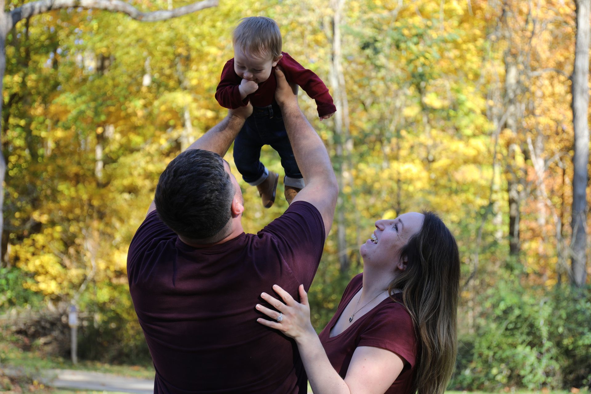 A man and woman are holding a baby in the air.