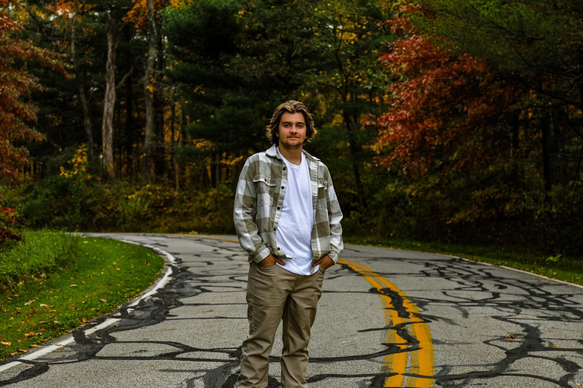 A man in a plaid shirt is standing on the side of a road.