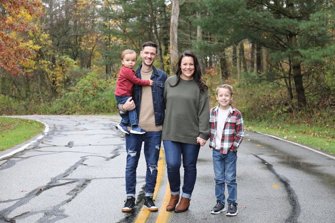 A family is standing on the side of a road holding hands.