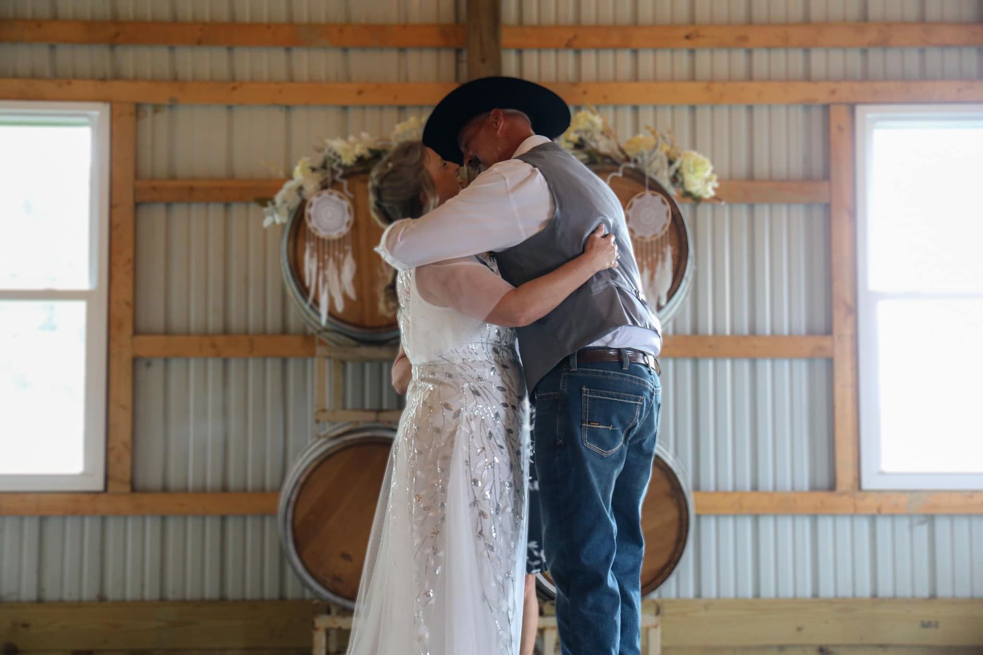 A bride and groom are kissing in a barn.