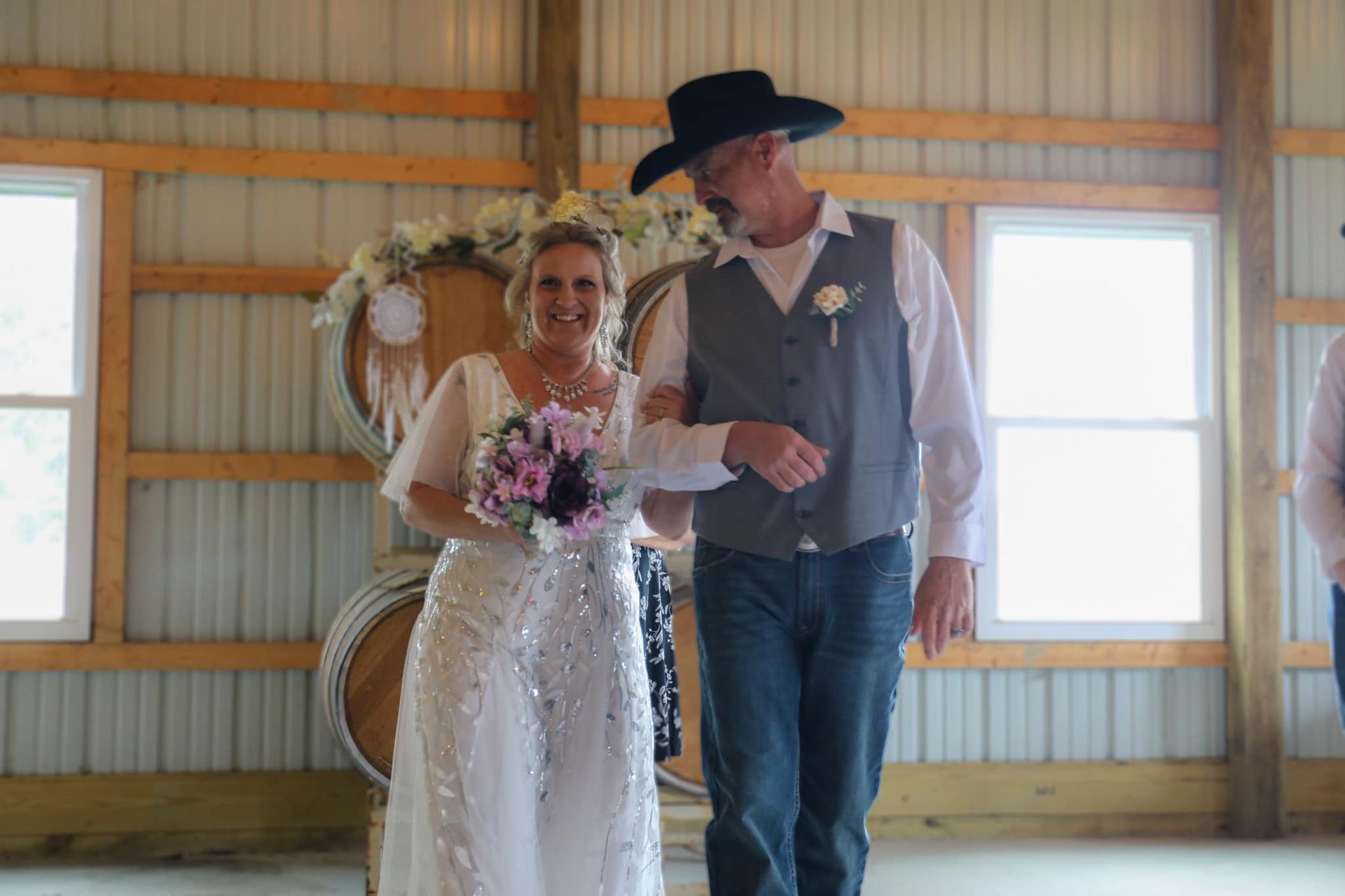 A bride and groom are walking down the aisle at their wedding in a barn.