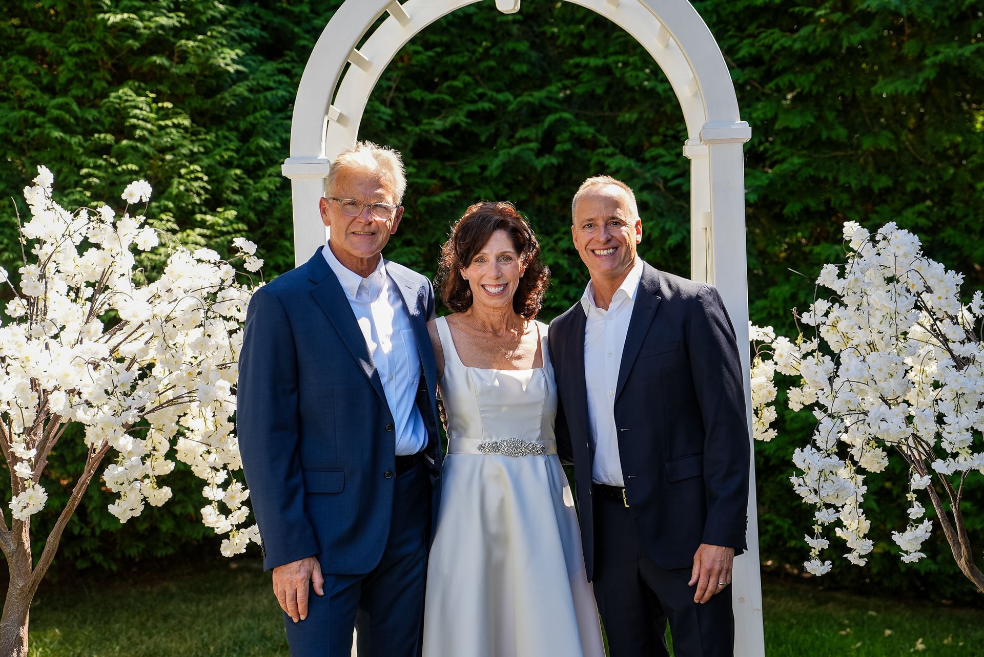 A bride and groom are posing for a picture with their parents.