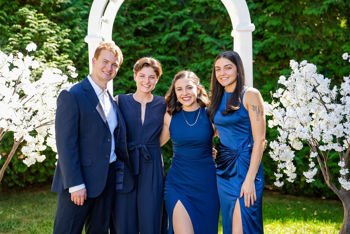 A group of people are posing for a picture in front of a white archway.