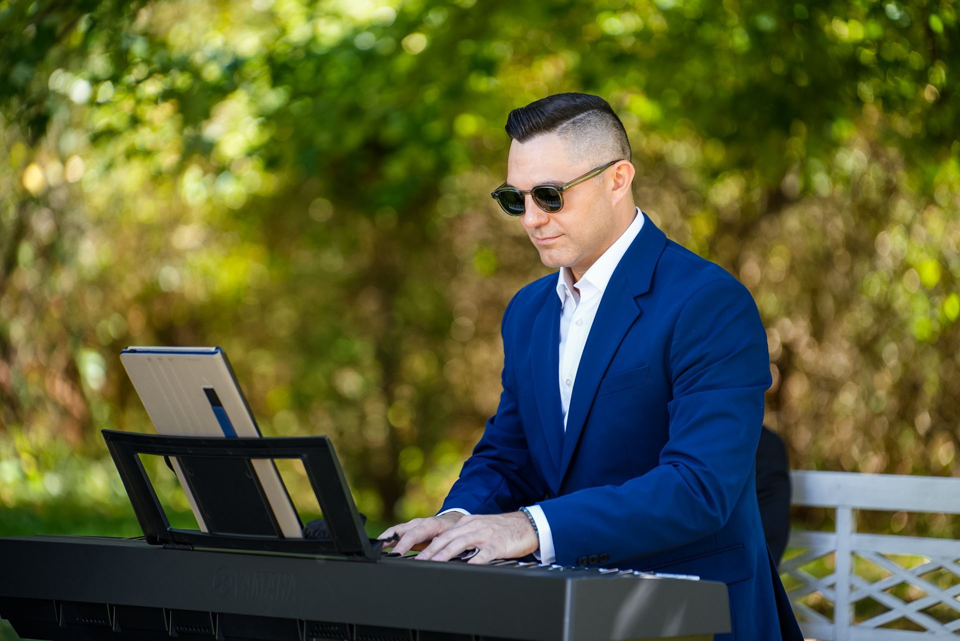 A man in a blue suit is playing a keyboard outside.