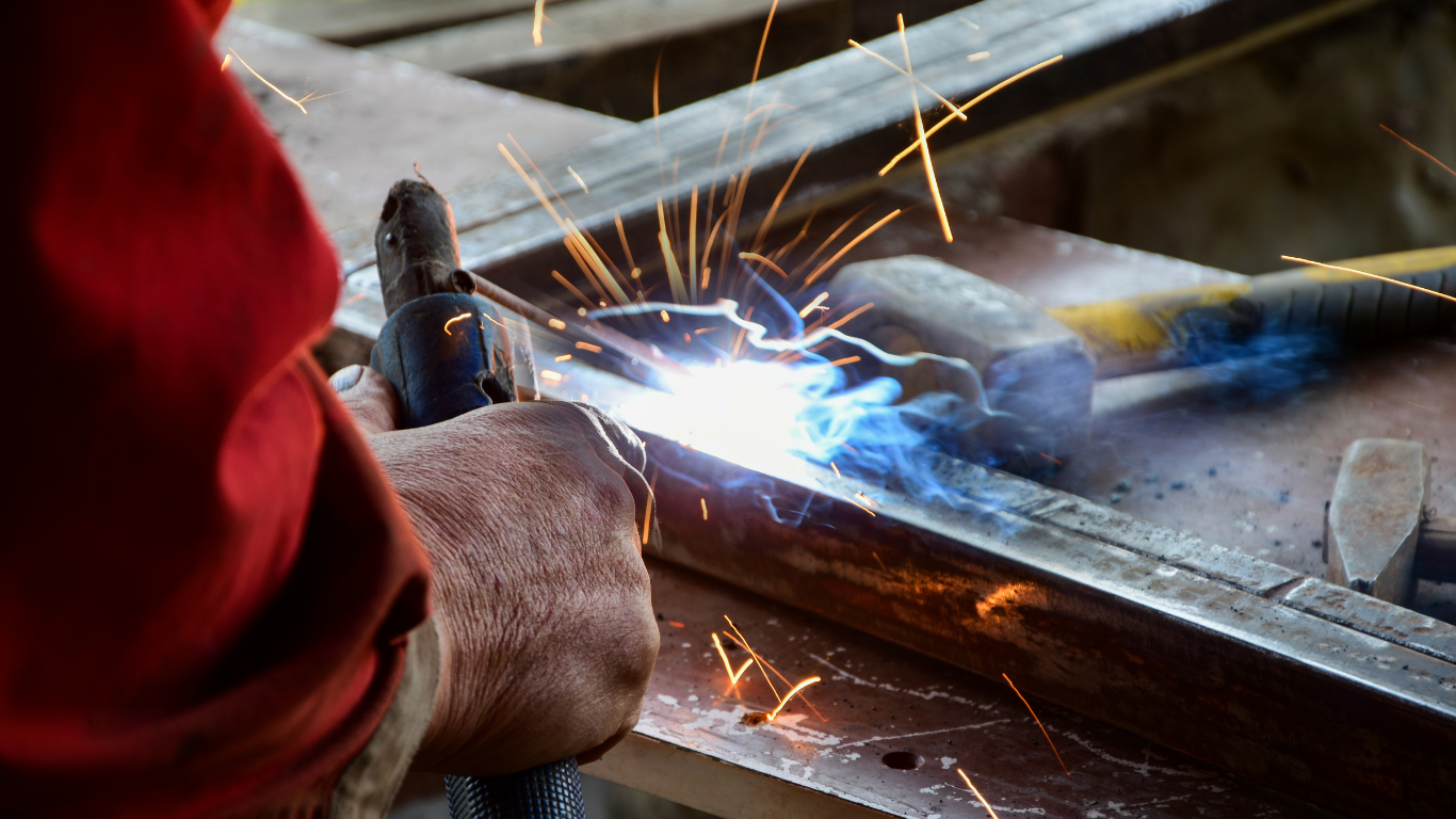 Person welding metal with bright sparks in a workshop.