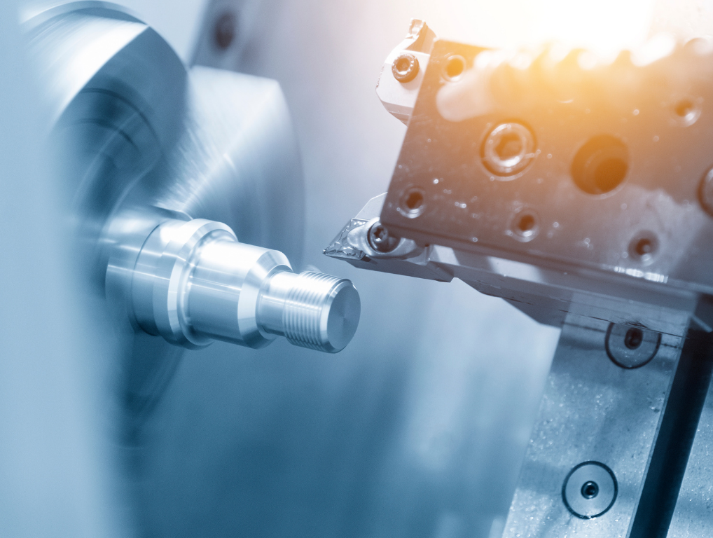 Metal lathe machining a cylindrical metal part.