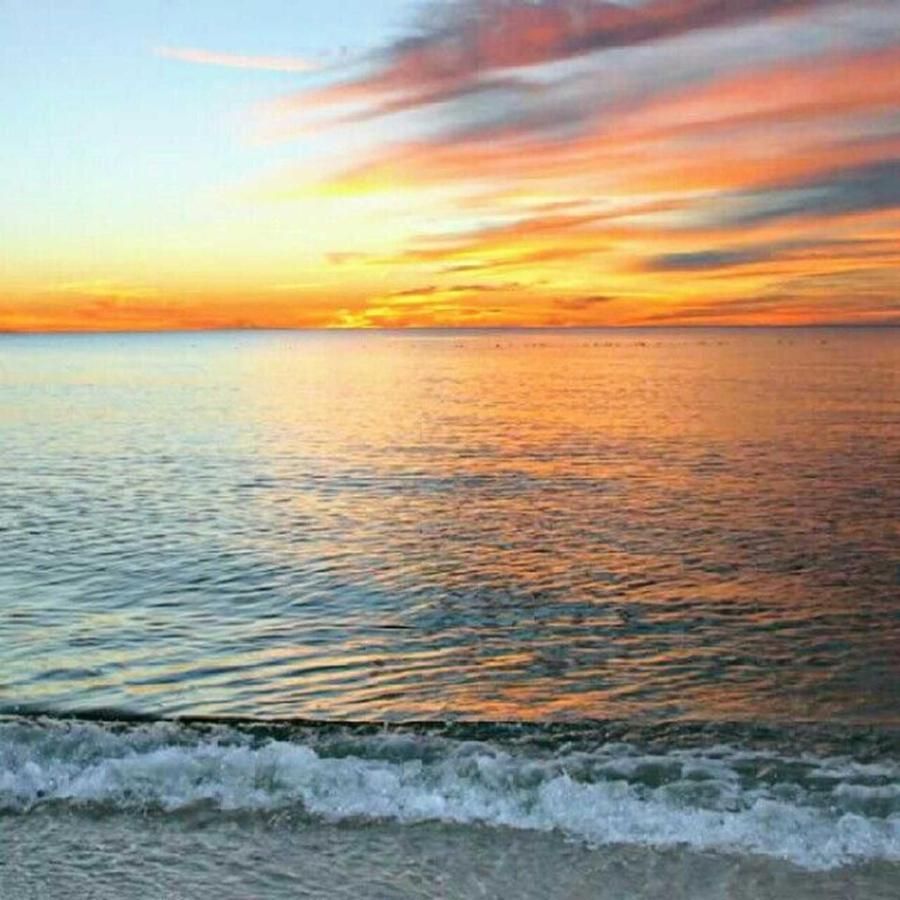 A sunset over the ocean with waves crashing on the beach