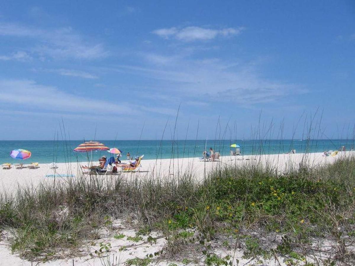 A group of people are sitting under umbrellas on a beach.