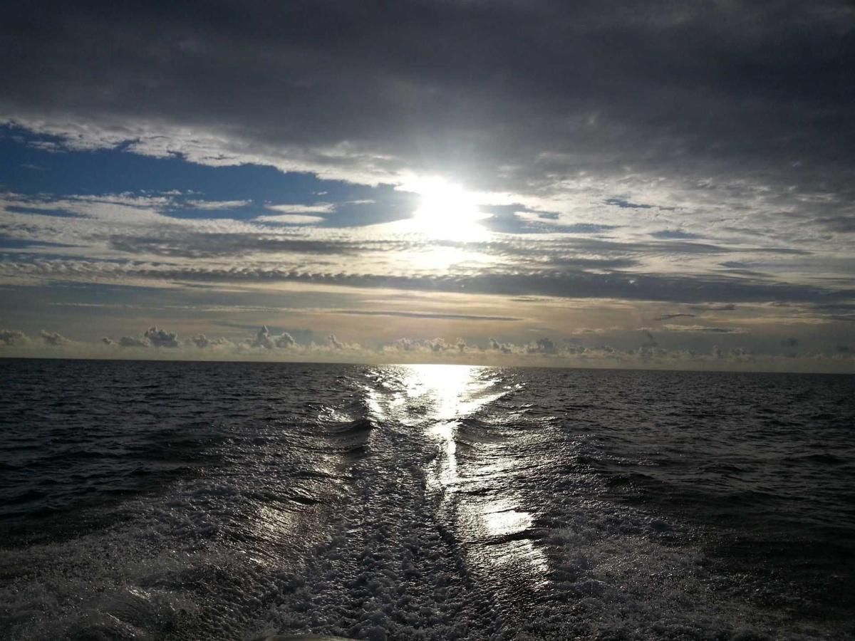 The sun is shining through the clouds over the ocean